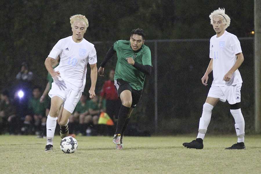 Senior Quinn Douglas (10) gets past a North Lenoir defender with senior teammate Crewe Douglas standing by during Saturday's 8-1 victory in the second round of the playoffs. Their bright blond hair is a result of a team-bonding activity for the playoffs. PHOTO BY BUZZY STATEN/Nighthawk News Magazine