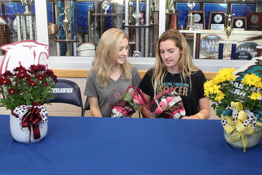 Anne Elliott Taylor (left) and Brayleigh Jones visit with each other during their signing ceremony at the school on Feb. 7. PHOTOS BY BUZZY STATEN/Nighthawk News