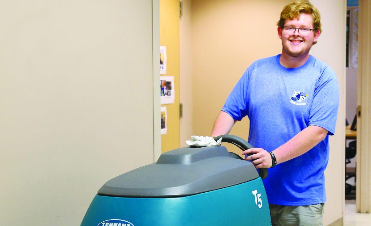 Josh Holland uses a machine to clean floors after school. A First Flight graduate, Holland has come back to school to work with the custodial staff. PHOTO BY BUZZY STATEN / Nighthawk News