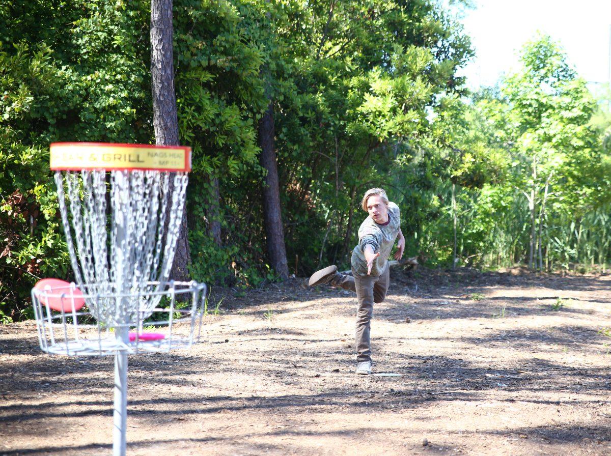 Junior Ethan White sends his disc flying toward the basket to finish off the hole.