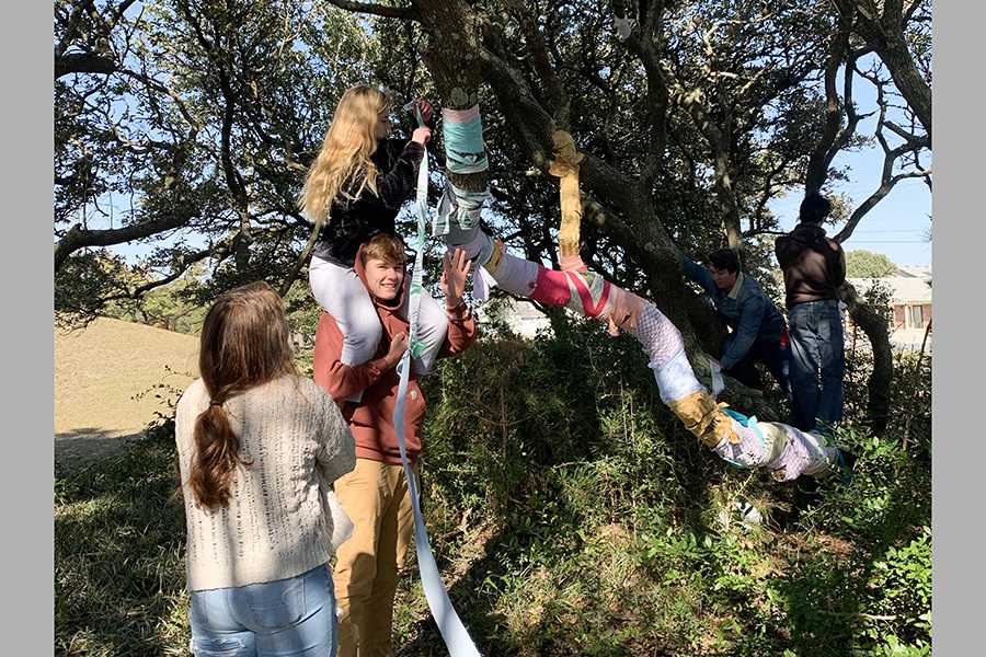 Sophomore Aubrey Holland gets a boost from junior Robert Peters as art students help with the Tress of Hope art installation at the Kill Devil Hills library last month. PHOTO BY ALICE BALDWIN/Special to Nighthawk News