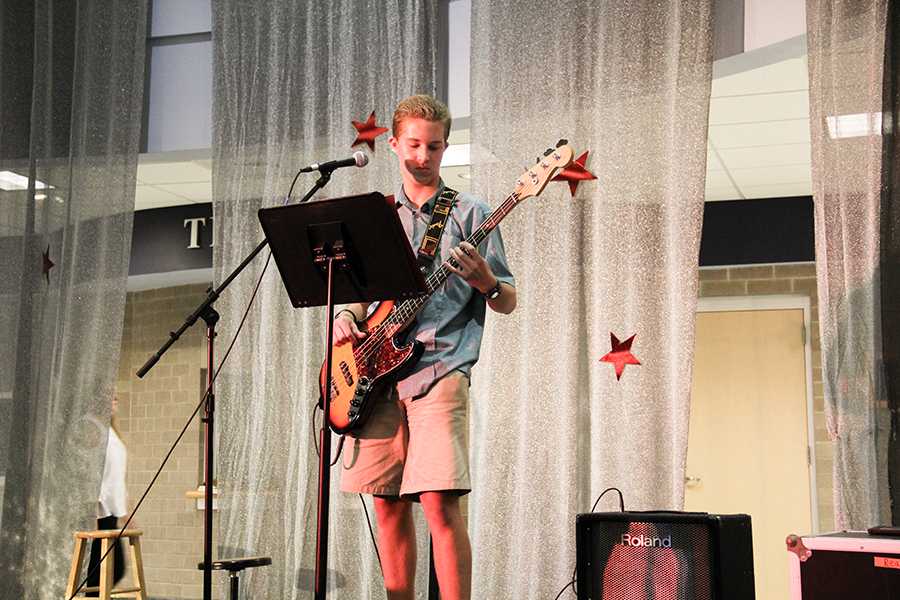 Sophomore Isaac Drummond strums the bass guitar at Cabaret Night at First Flight, where students performed acts for an audience in the rotunda as a fundraiser for the fine arts programs. PHOTO BY EMMY TRIVETTE/Nighthawk News