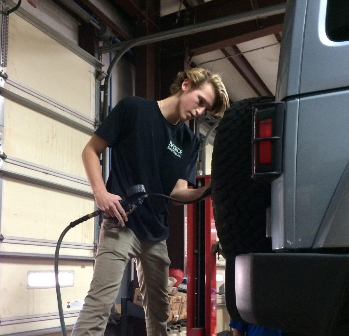 Senior Myles Sillies puts air in a tire at Bayside Body Shop during his internship. Sillies hopes to continue this line of work and eventually start a business in the auto industry. PHOTO BY KATHY NEAL/Special to Nighthawk News